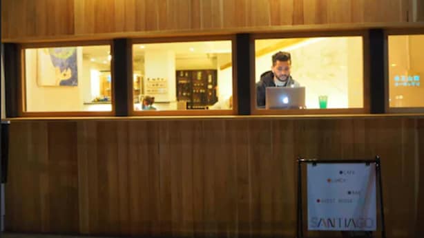 A hotel interior with wooden paneling, a reception area, and a signboard indicating amenities like a cafe, restaurant, and guest house. - Santiago Guesthouse Kyoto (Kyoto)