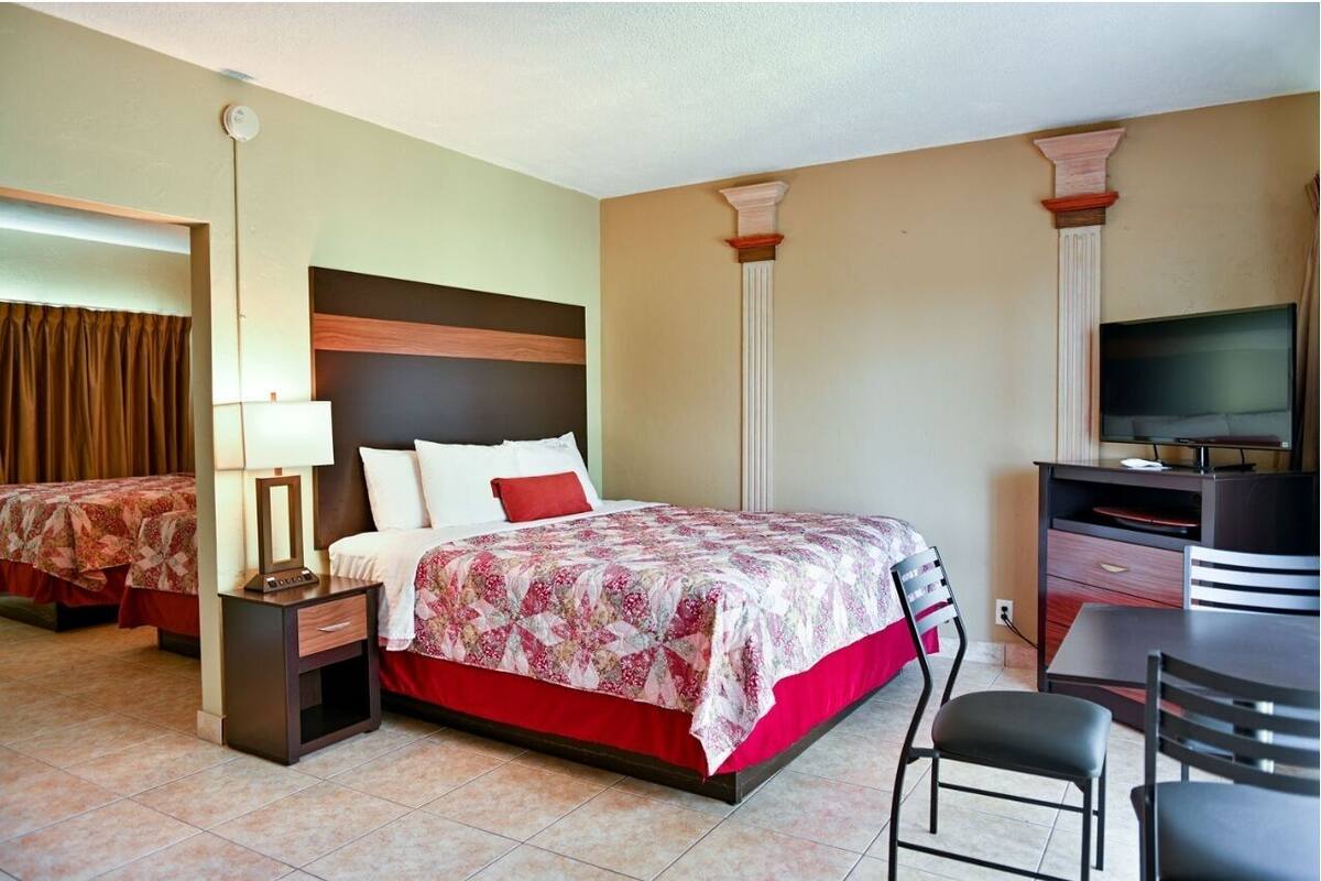 A hotel room with a bed, a desk, and a television.