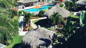 Un resort con piscina, estructuras de techo de paja y palmeras.