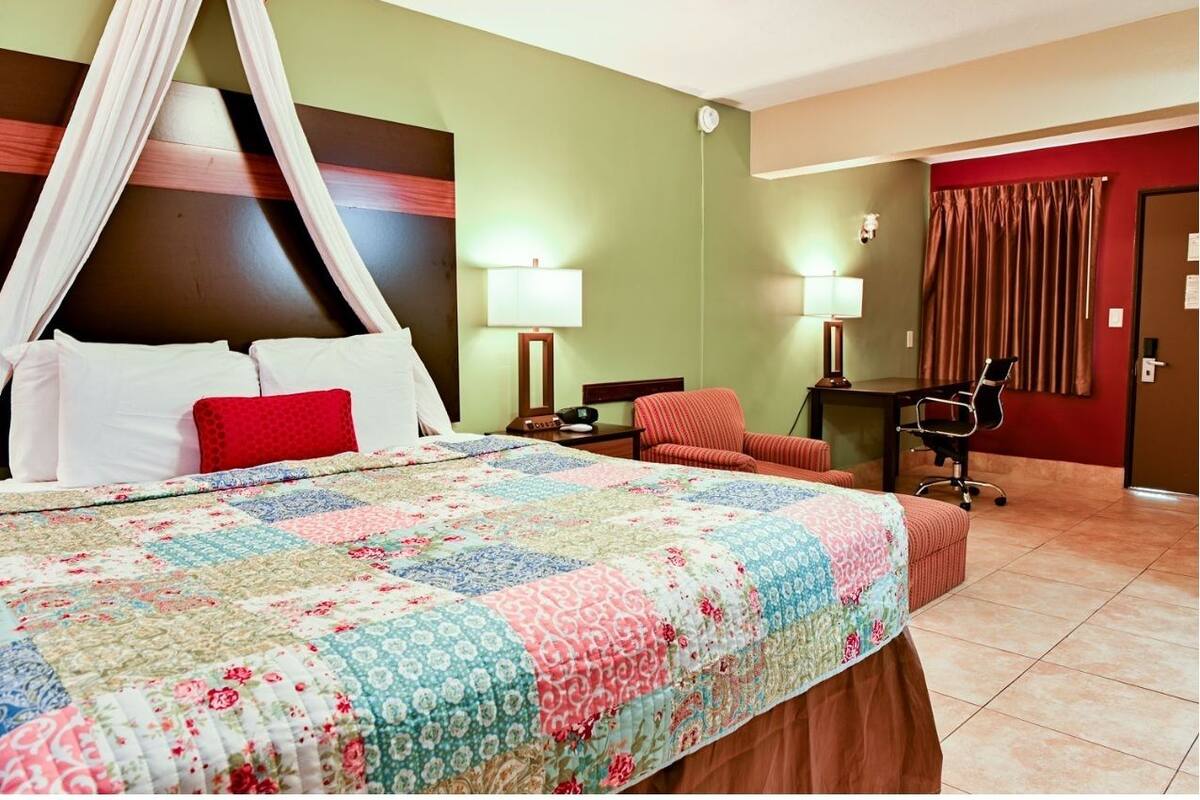 A hotel room with a bed, a desk, a chair, and a nightstand.