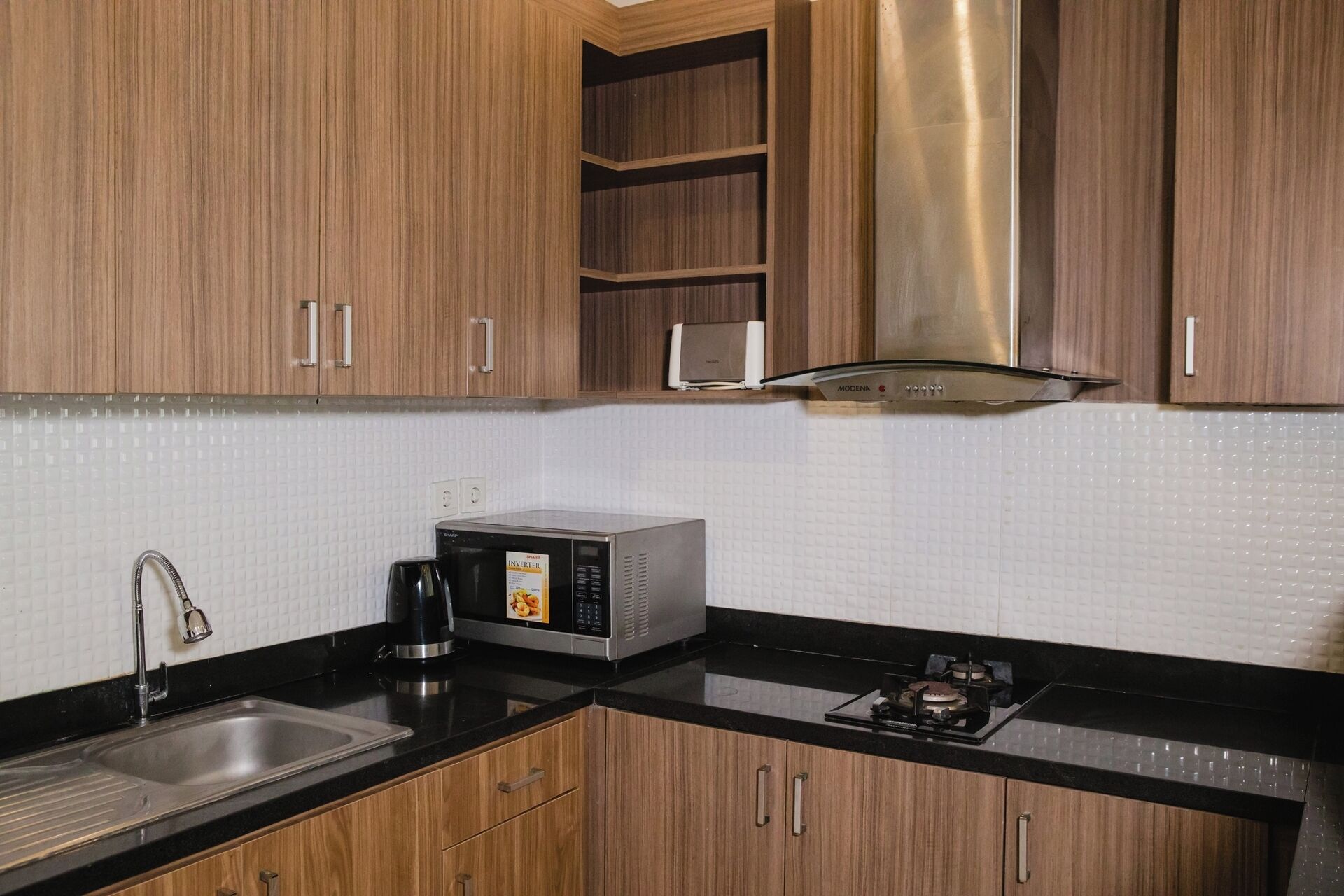 Una cocina con gabinetes de madera, una campana extractora de acero inoxidable, un microondas y una estufa a gas.