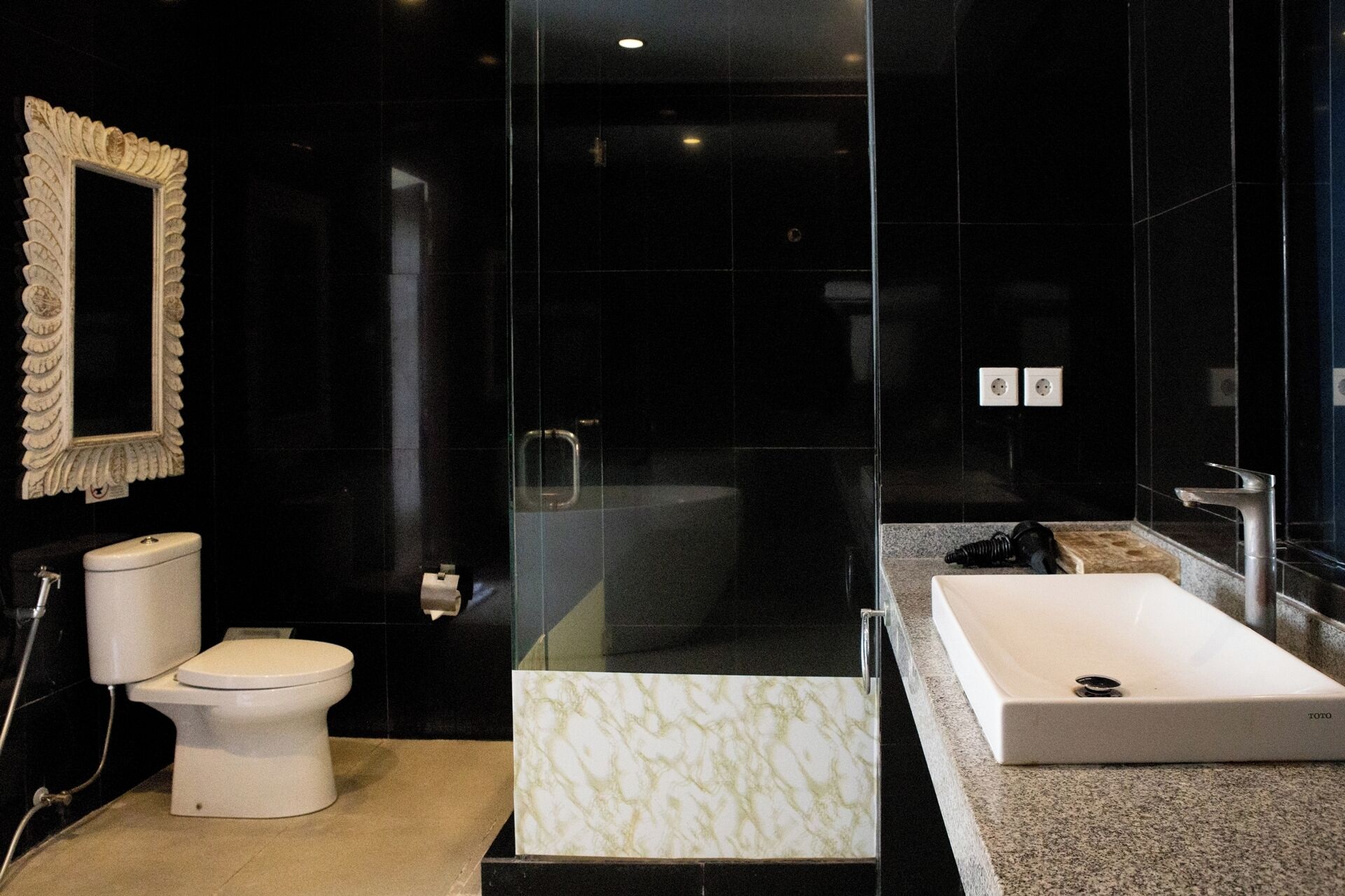 A modern bathroom with a toilet, a glass-enclosed shower, and a large rectangular sink.