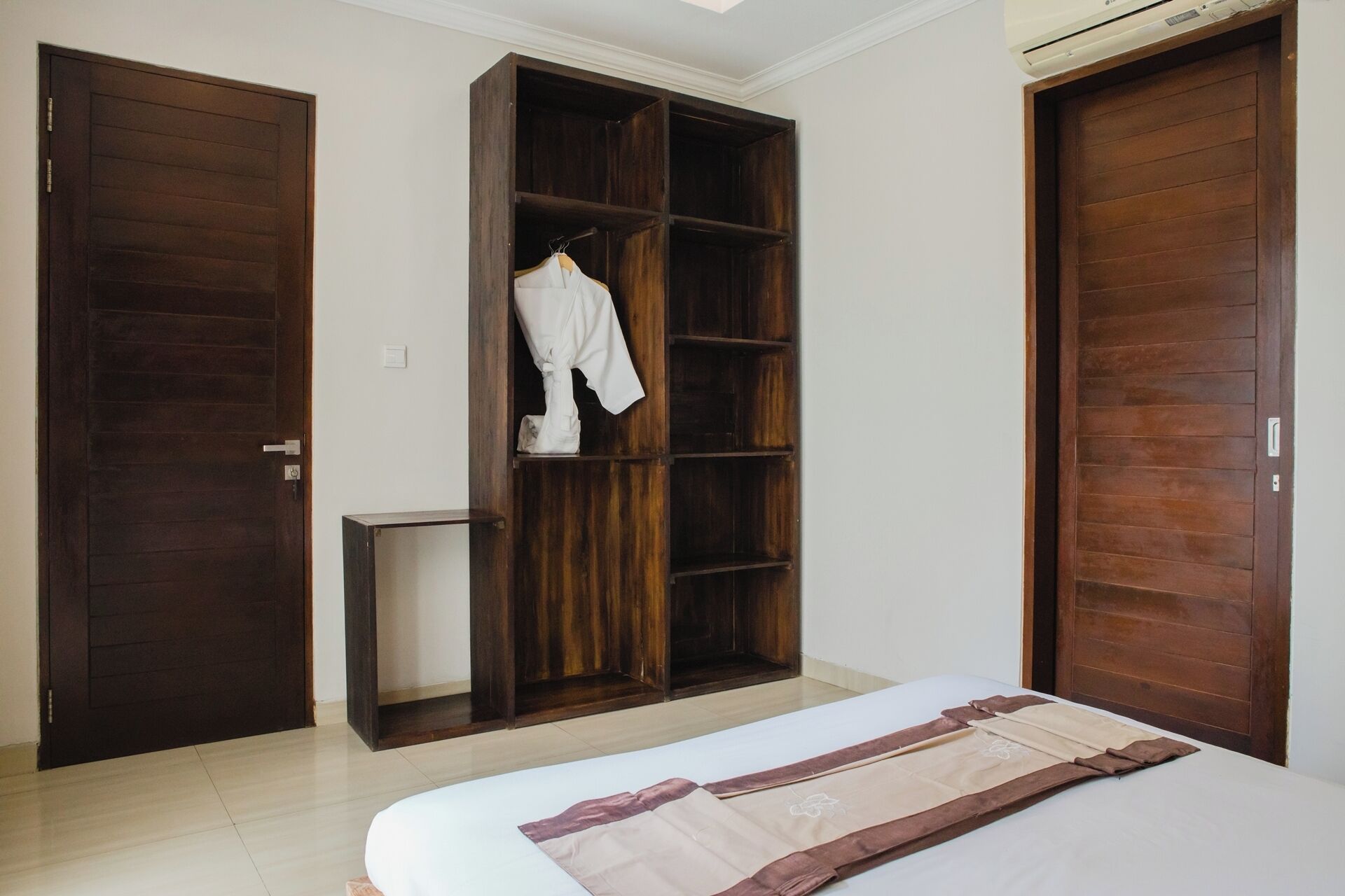 A bedroom with a bed, a wardrobe, and a small table.
