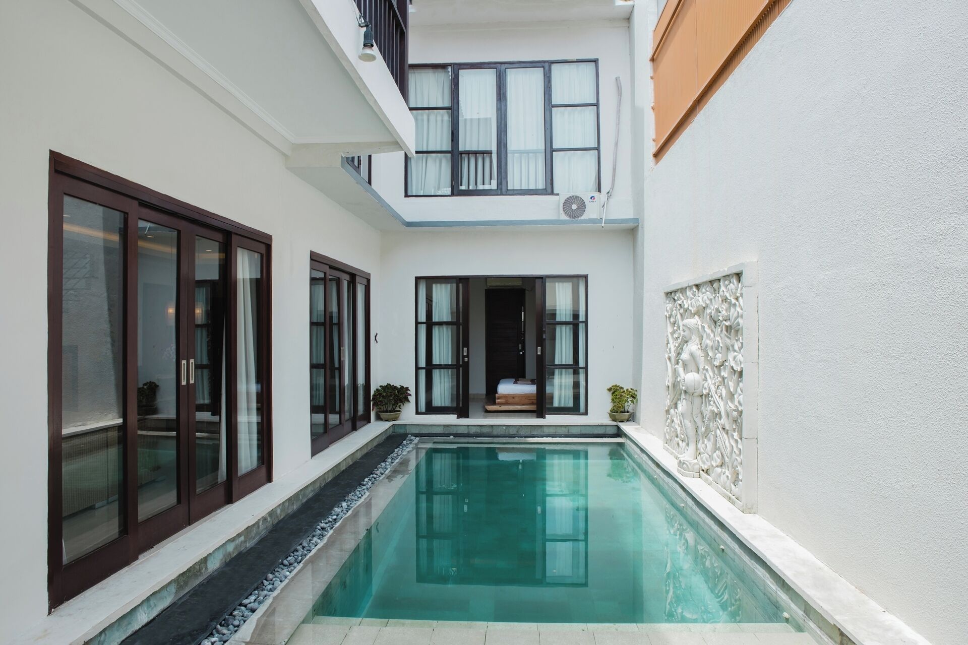 A modern house with a swimming pool, large windows, and a balcony.
