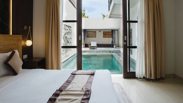 Habitación de hotel con una cama grande, vistas a una piscina y un balcón.