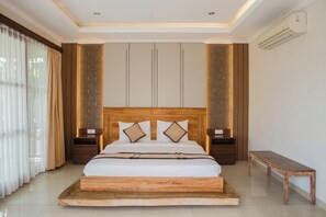 A bedroom with a large bed, wooden headboard, and matching nightstands. - White Lotus Villas Seminyak (Seminyak)