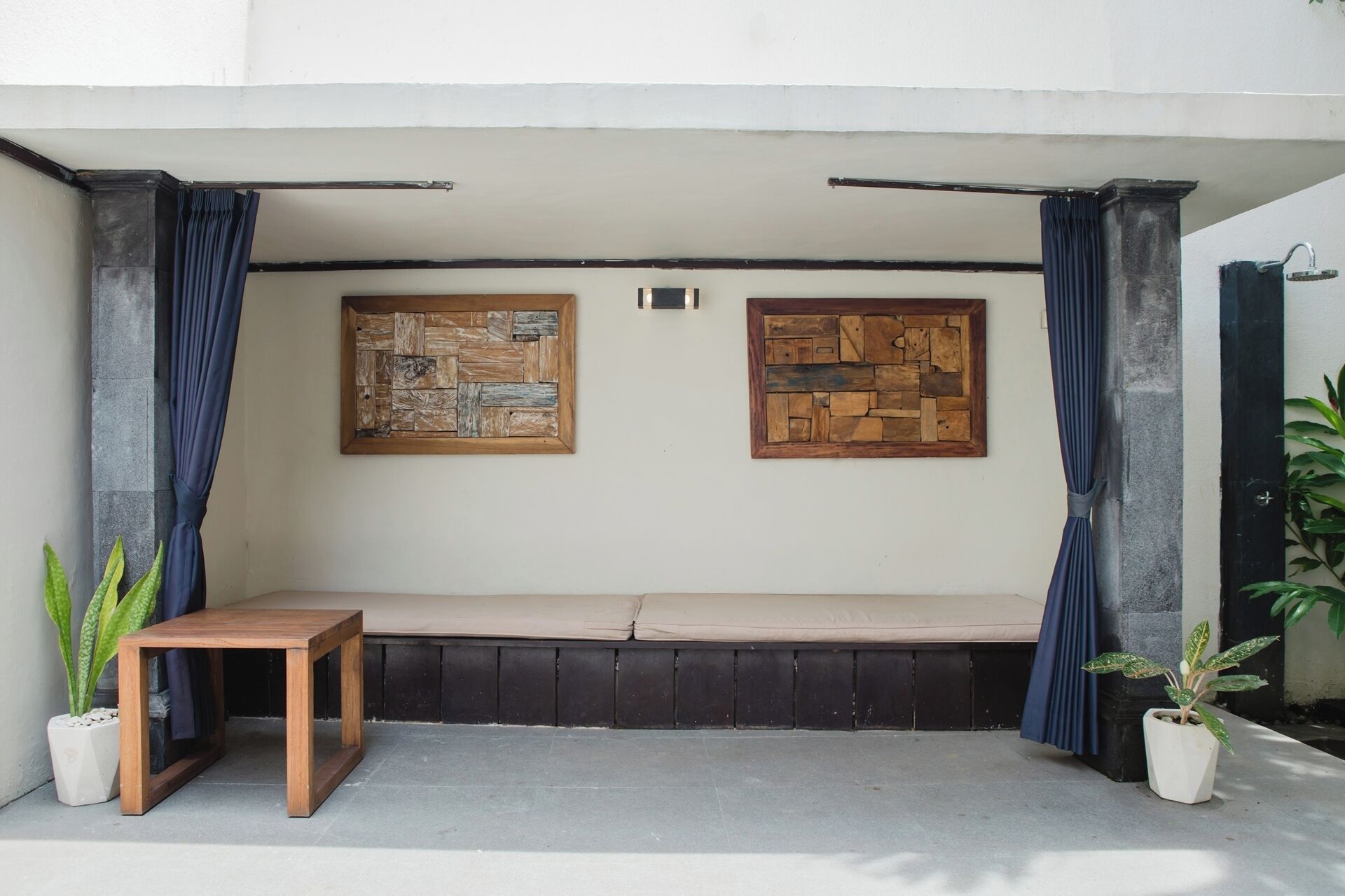 A seating area with a bench, two wooden wall art pieces, and potted plants.