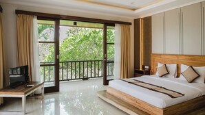 Un dormitorio con una cama grande, televisión y balcón con cortinas.