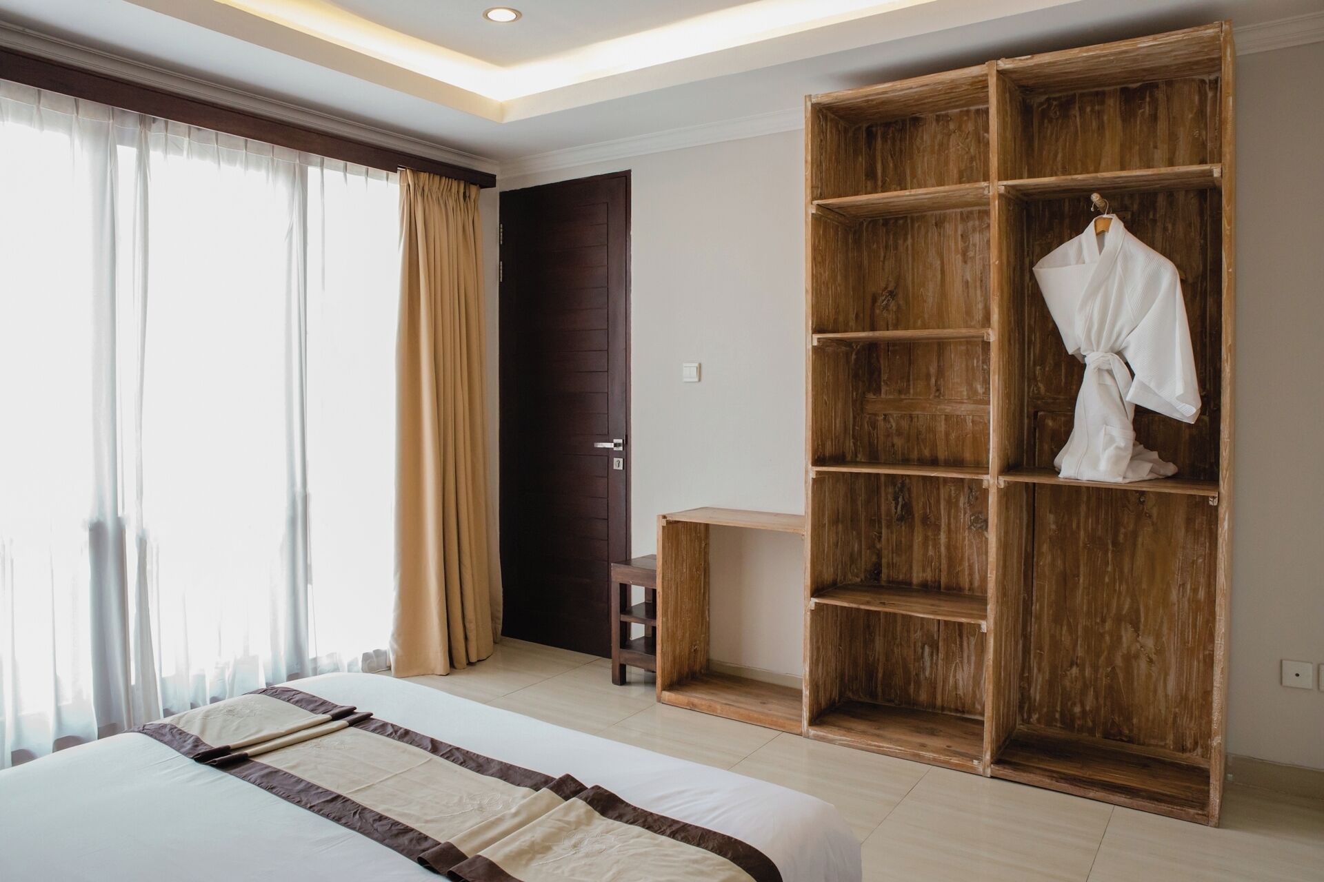 Una habitación de hotel con una cama grande, un armario de madera y un banco.