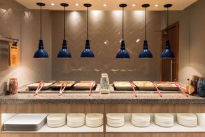A buffet setup with multiple serving stations, plates, and utensils. - Hampton by Hilton Birmingham Jewellery Quarter (Birmingham)