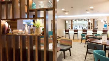 Eine moderne Hotelhalle mit Holzwänden, Sitzbereichen und einer Bar im Hintergrund.