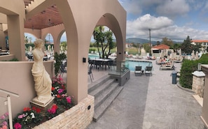 Zona de piscina con estatua, asientos al aire libre y vistas del paisaje.