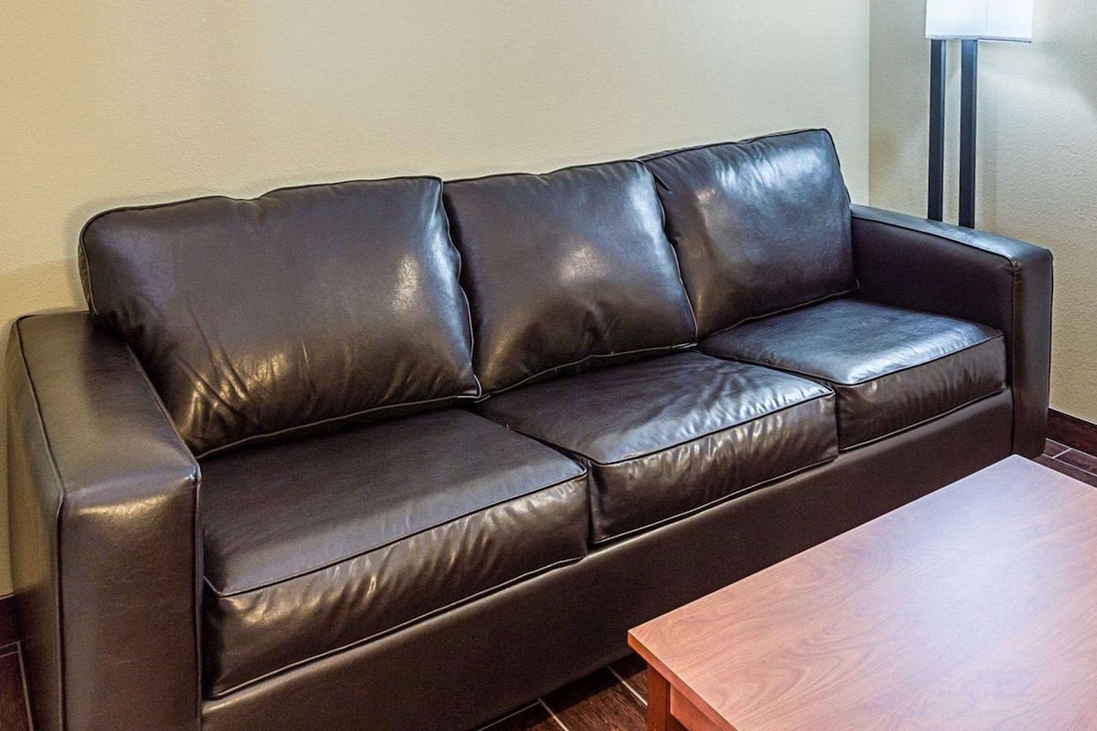 A brown leather sofa with a wooden coffee table in front.