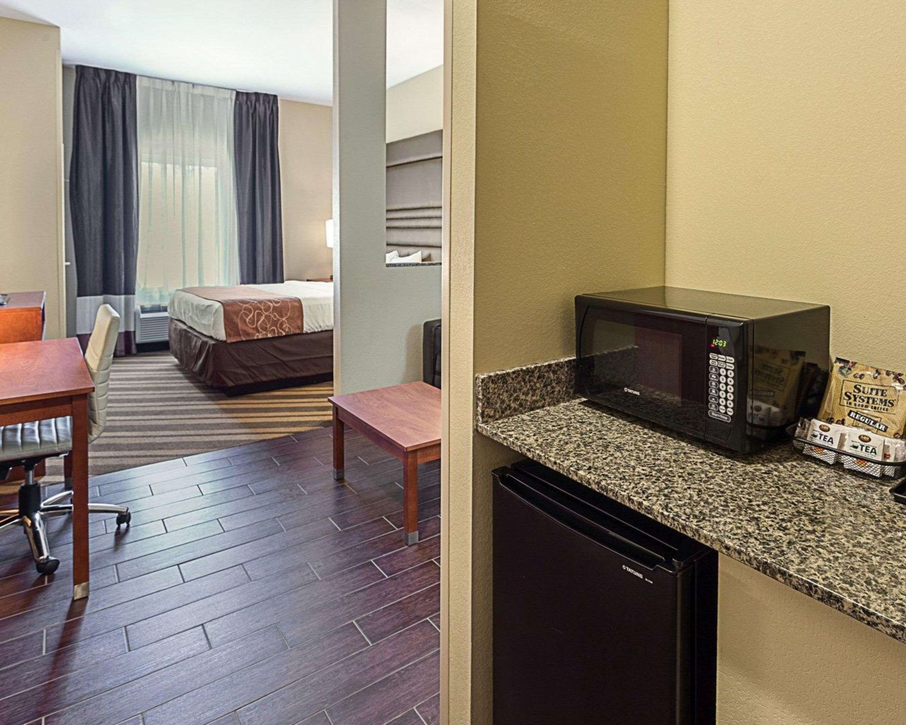 Habitación de hotel con cama, escritorio, silla, microondas y cafetera.