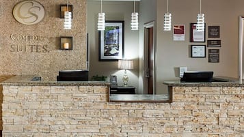 A reception area with a stone counter, a sign for 'Comfort Suites', and several framed pictures on the wall.