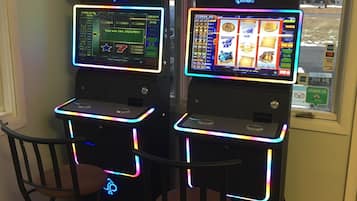 Dos máquinas tragamonedas con luces de neón, cada una mostrando un premio mayor de $12000.00.