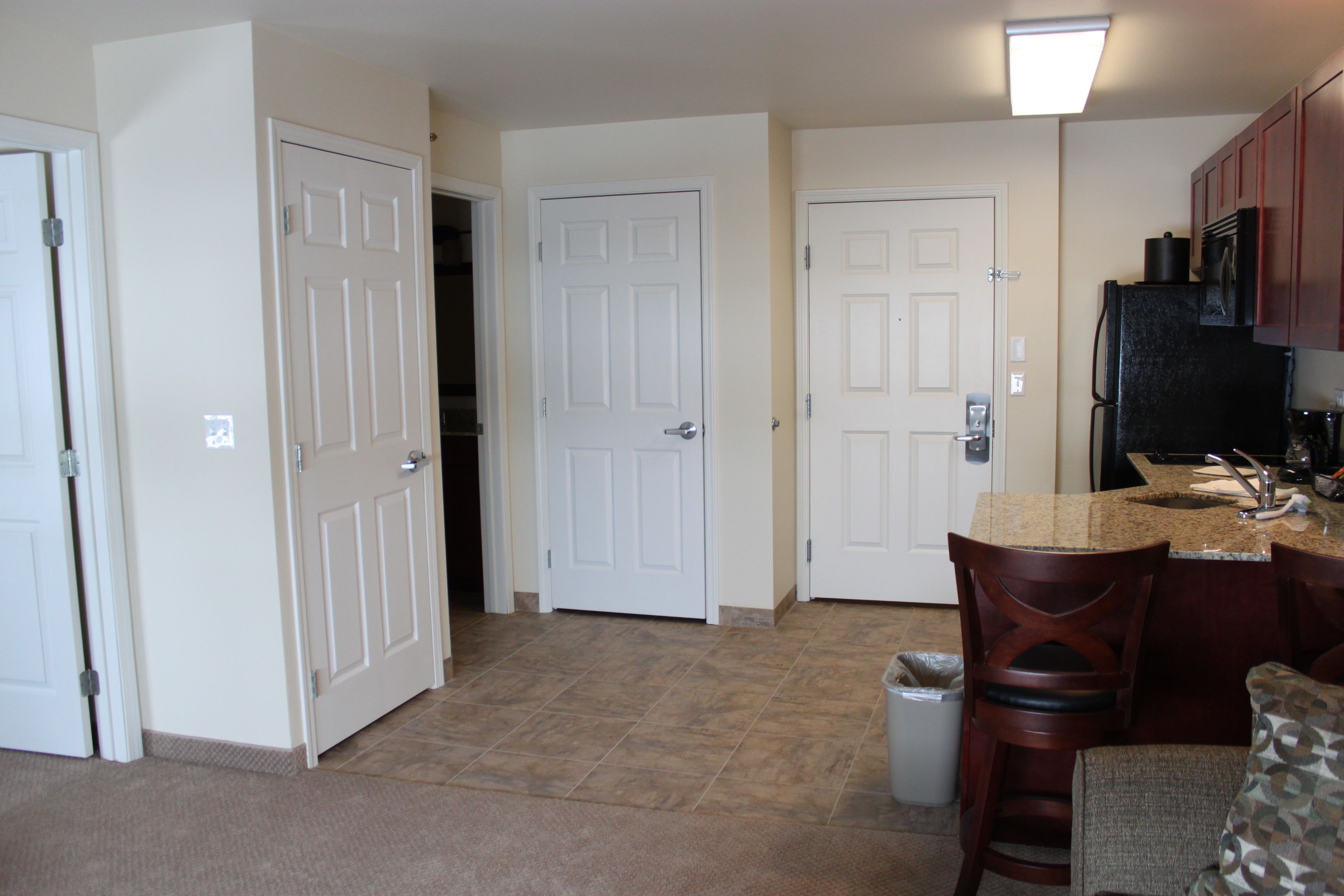 A kitchen with white doors, a granite countertop, and a black refrigerator.