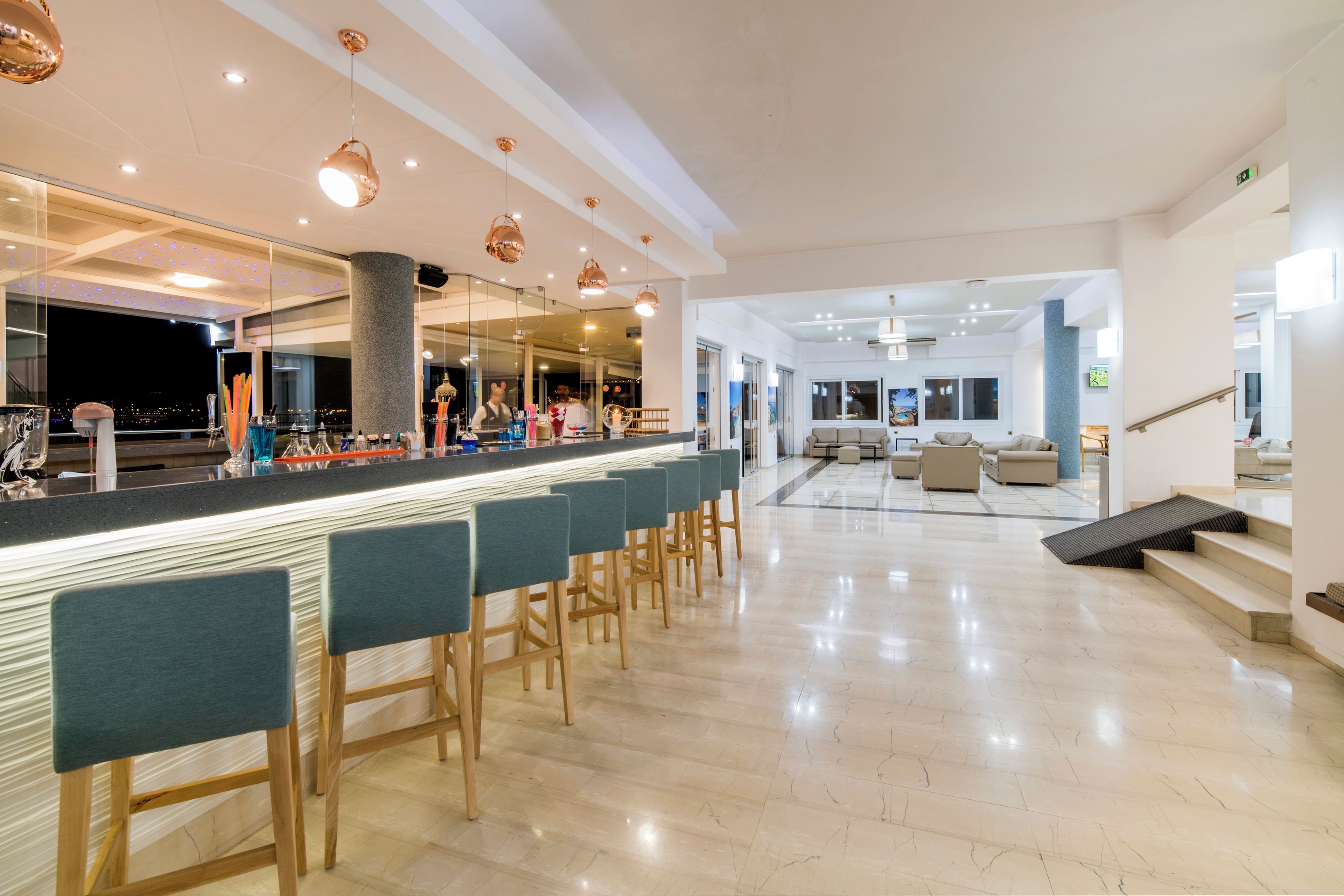 A modern bar area with a long counter, bar stools, and a glass partition.