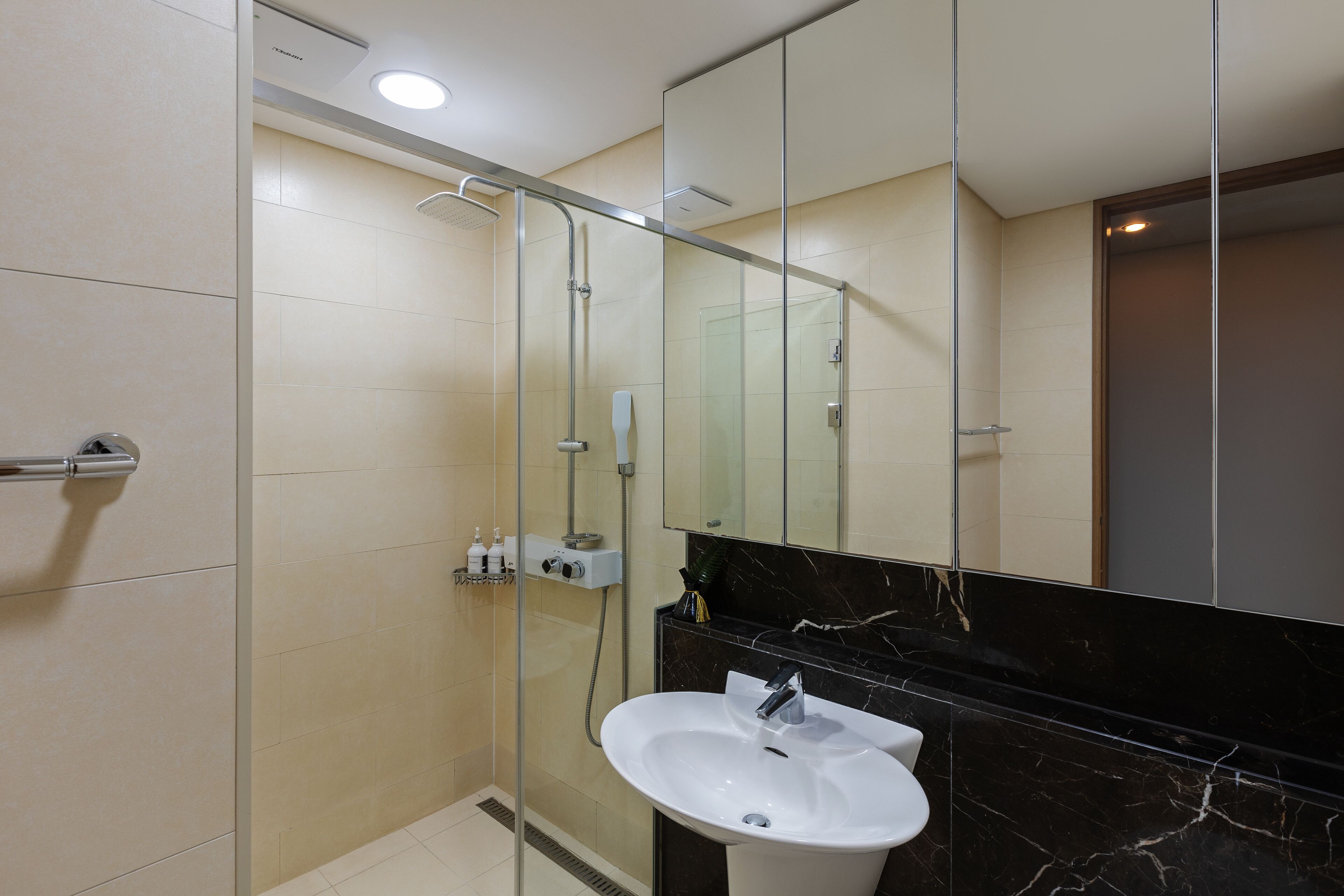 Een moderne badkamer met een glazen douchecabine, een wit wastafelmeubel en een grote spiegel.