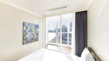 Un cuarto de hotel con una cama grande, un ventanal con vistas y un cuadro en la pared.
