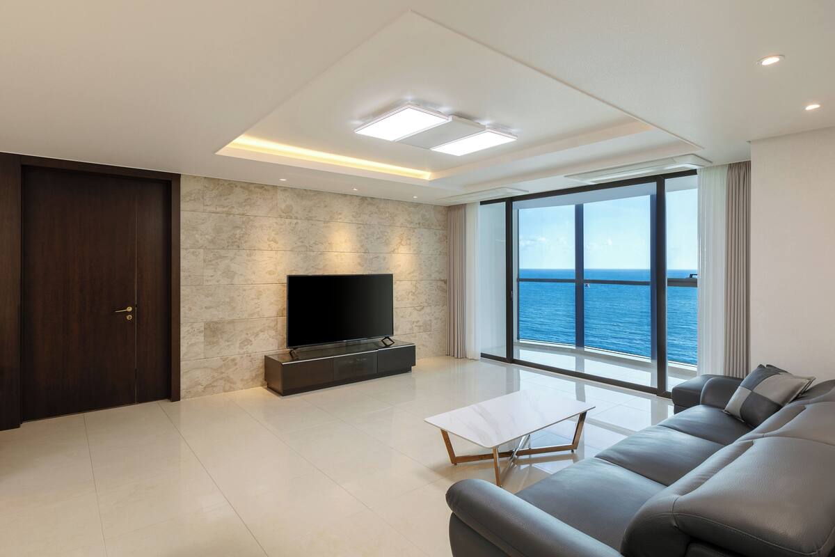 Una sala de estar moderna con un televisor de pantalla plana grande, un sofá y una mesa de centro.