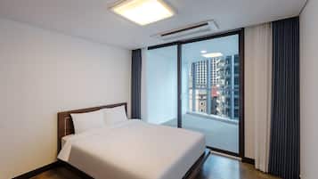 Una camera d'albergo con un letto grande, una finestra con tende e vista sugli edifici.