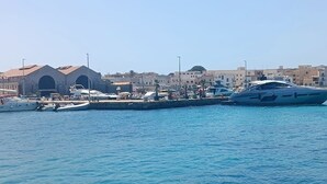 Uma marina com barcos atracados, um edifício com telhado vermelho e um céu azul límpido.