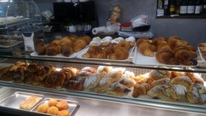 Vitrine de pastelaria com diversos doces e produtos de panificação.