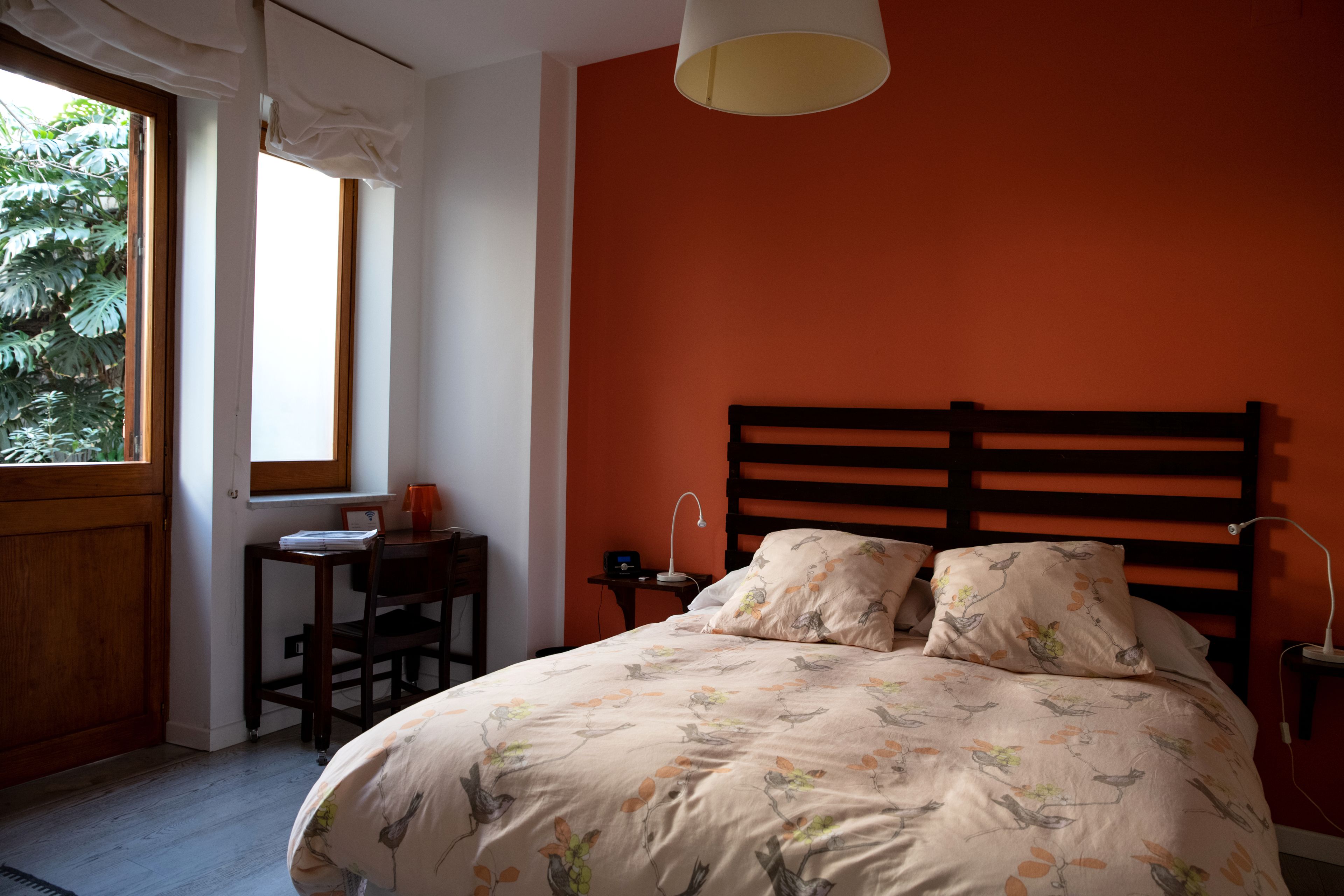A bedroom with a bed, a desk, and a window with curtains.