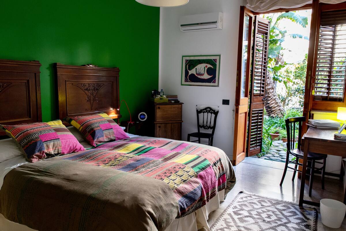 Un dormitorio con una cama grande, una mesita de noche de madera, una silla y un escritorio con lámpara.