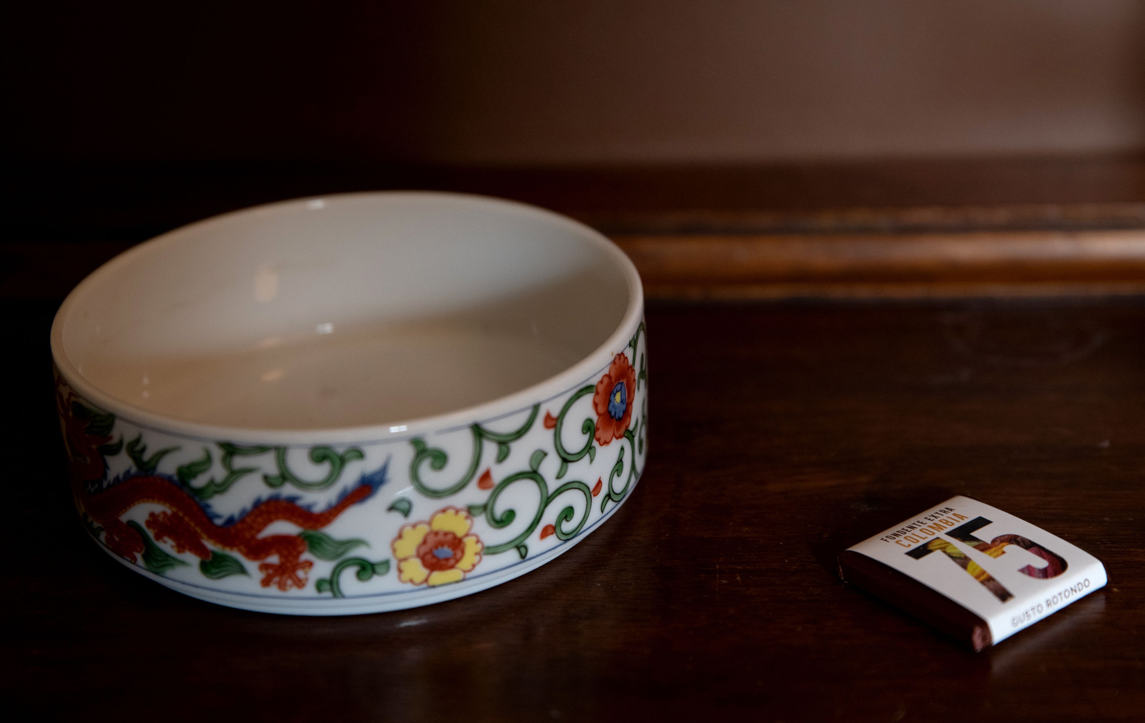 A bowl with a floral pattern and a book beside it.