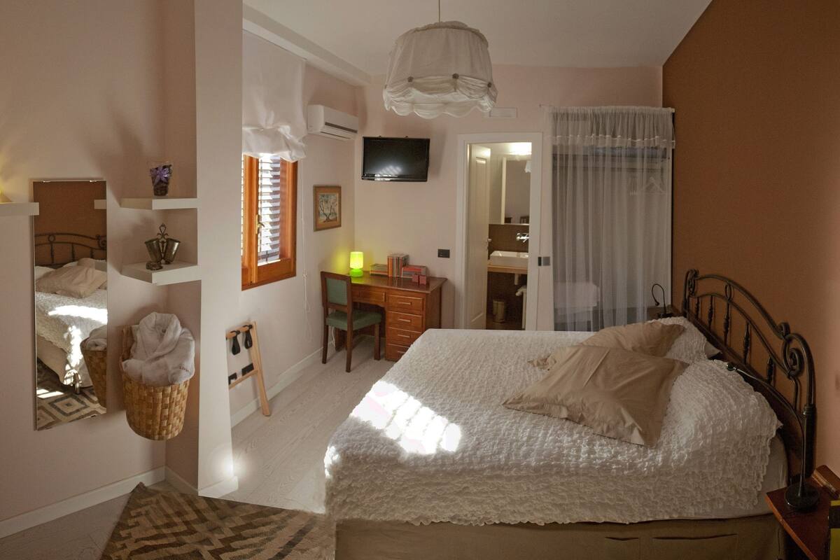 Un dormitorio con cama, escritorio, silla, armario y una cesta colgante.