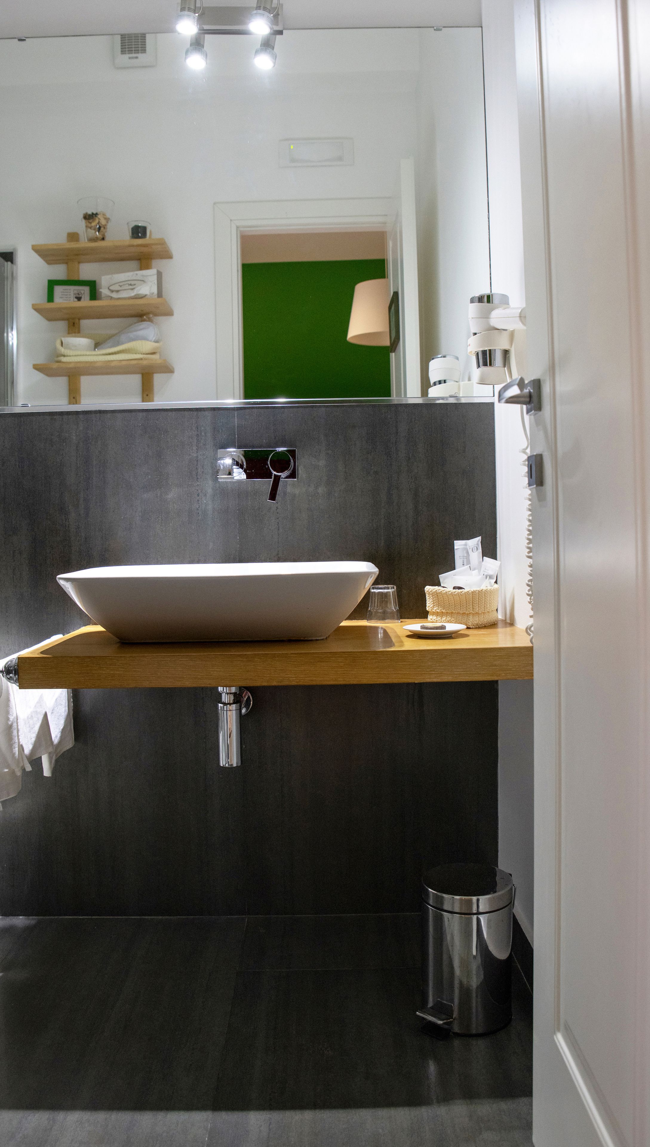 Un baño moderno con un lavamanos grande de color blanco, paredes gris oscuro y encimera de madera.