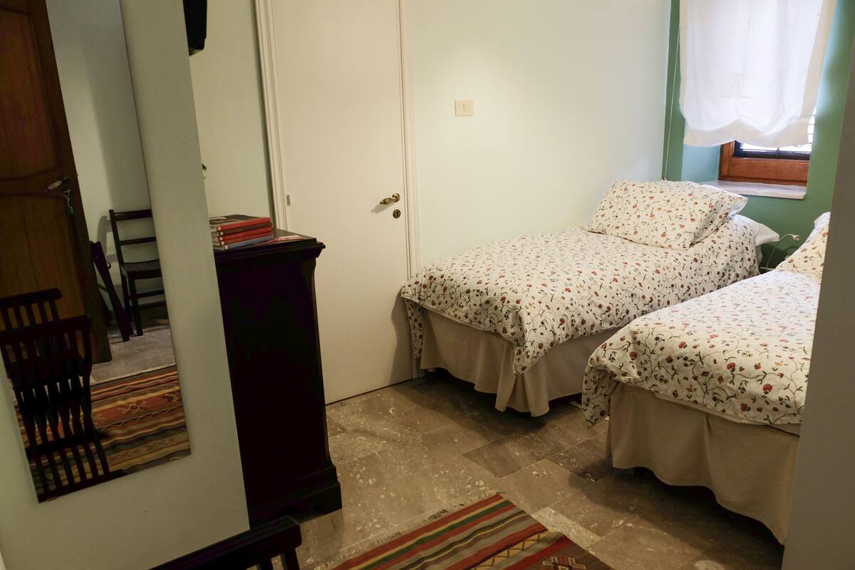 Un dormitorio con dos camas, un aparador de madera y una silla.