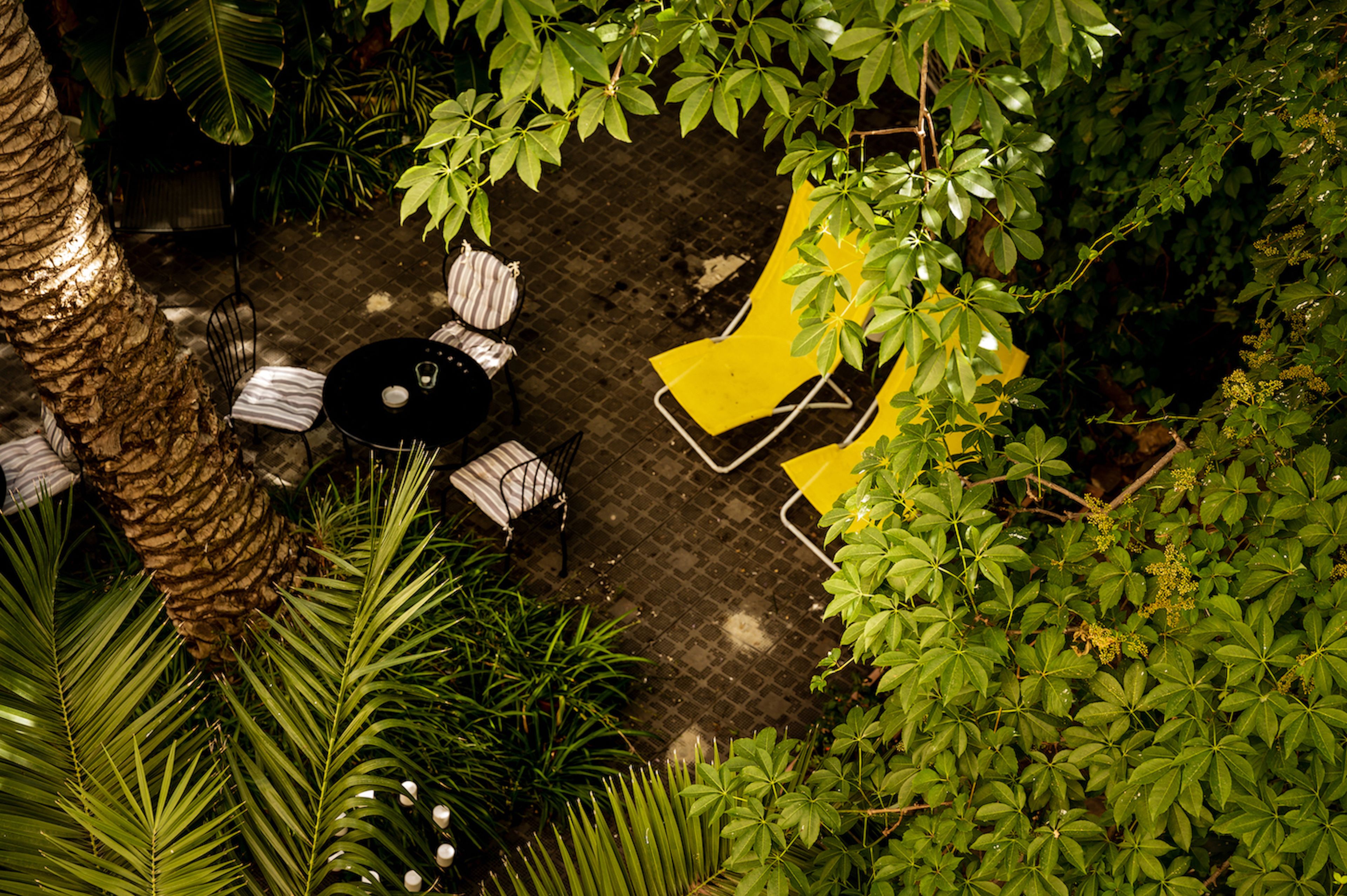 An outdoor patio area with a round table, two chairs, and a yellow lounge chair.