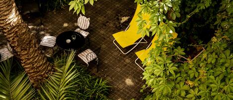 An outdoor patio area with a round table, two chairs, and a yellow lounge chair.