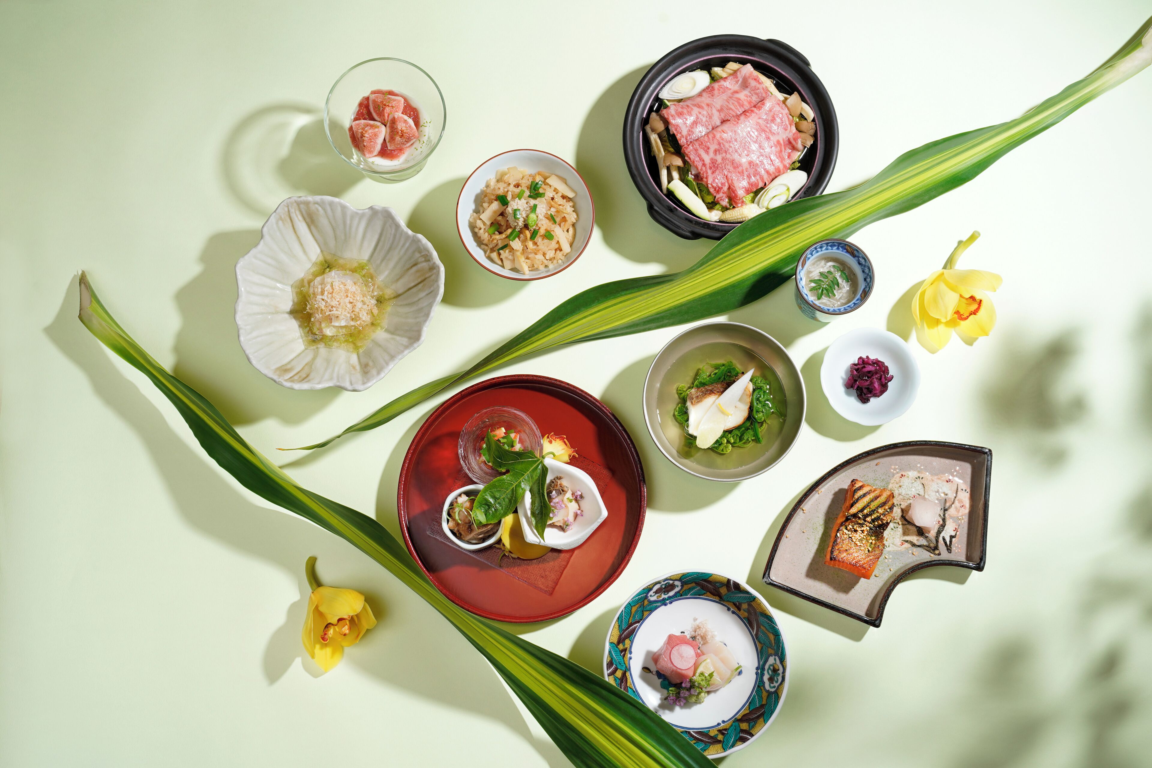 A variety of dishes and flowers on a table.