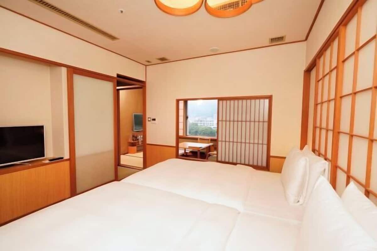 A hotel room with a bed, a television, a sliding door, and a window with a view.