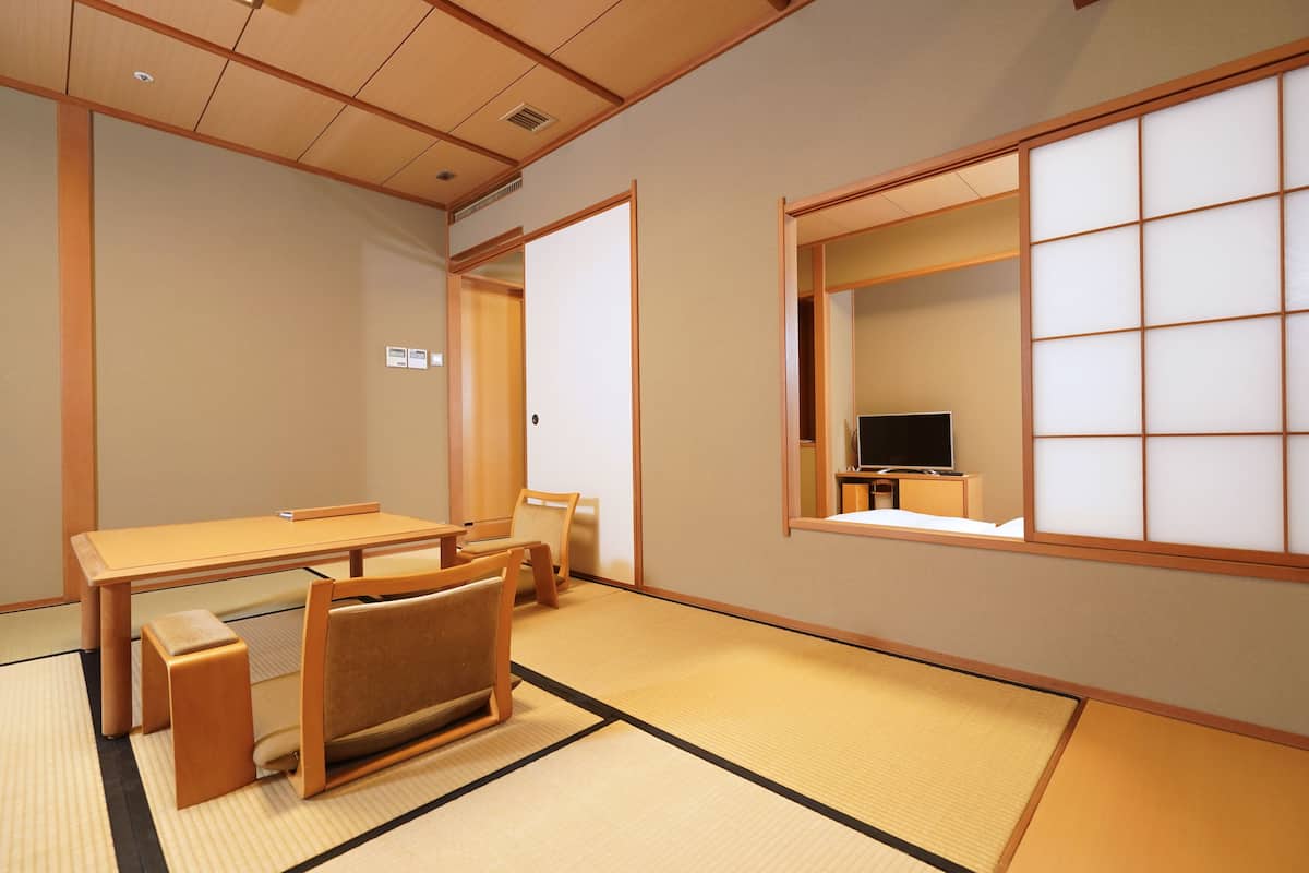 A traditional Japanese room with tatami flooring, a low table, a sofa, and sliding doors.