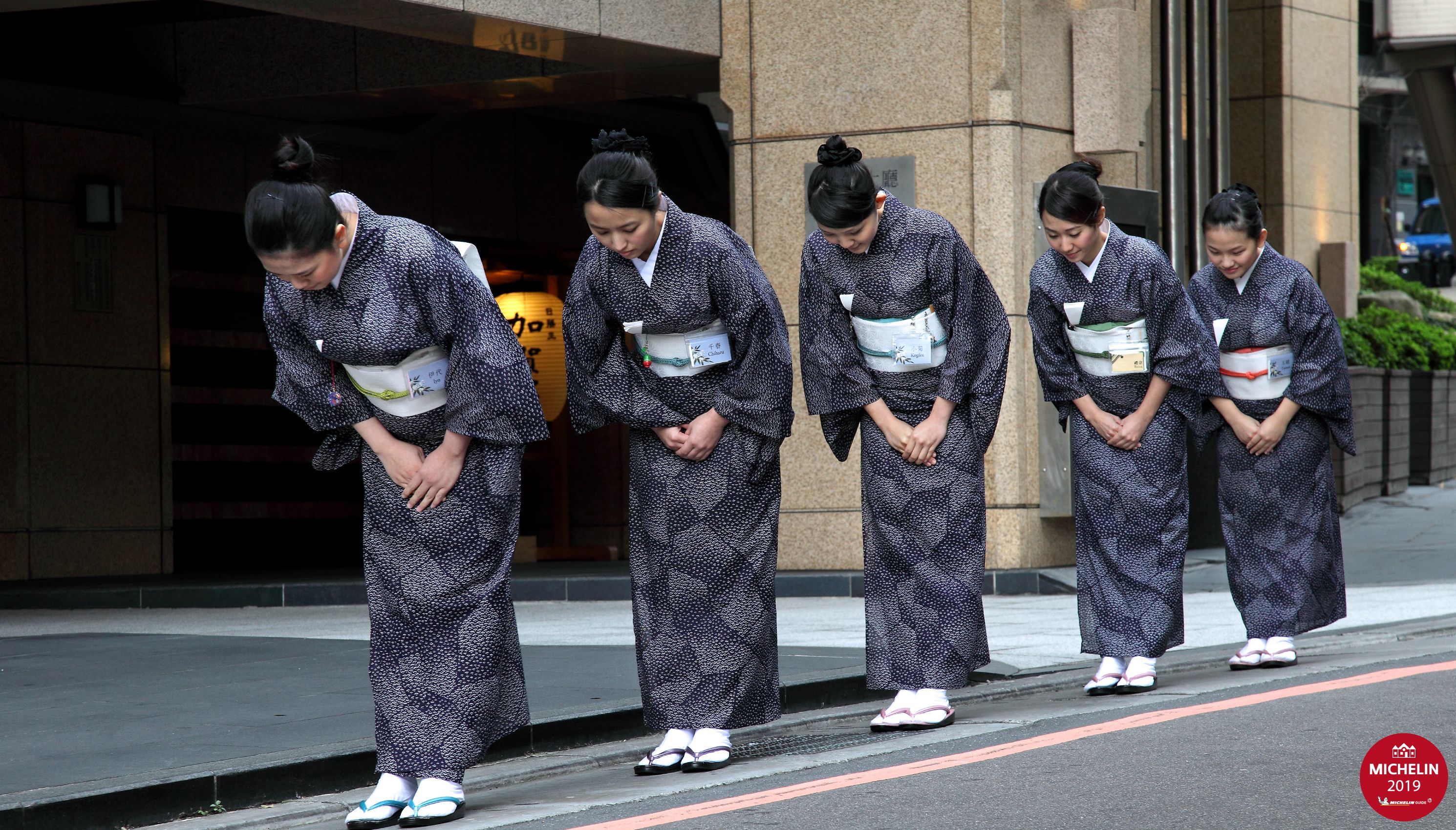 A row of individuals in traditional attire standing on a sidewalk.