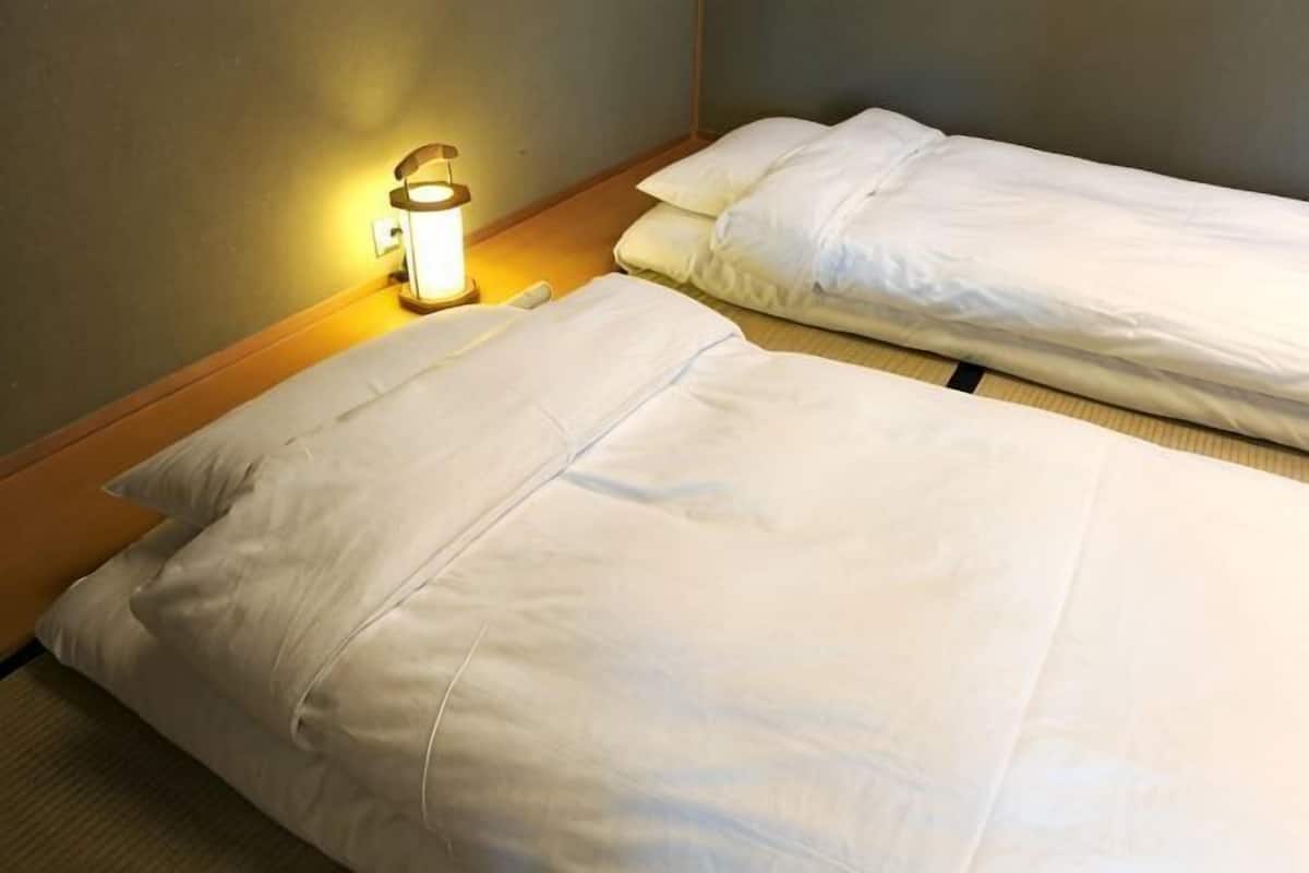 A hotel room with a bed, pillows, and a bedside lamp.
