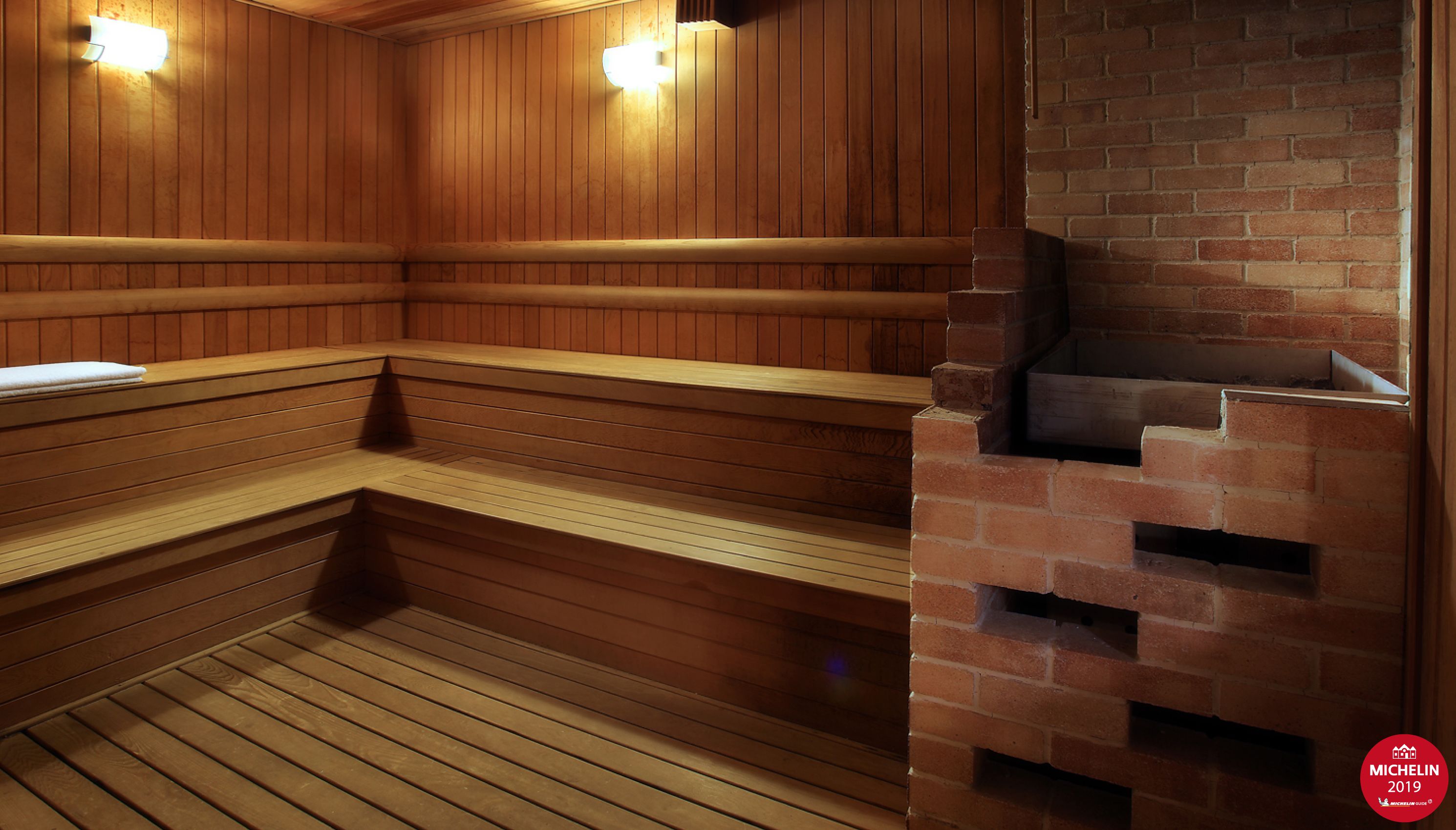 A sauna with wooden benches and a brick wall.