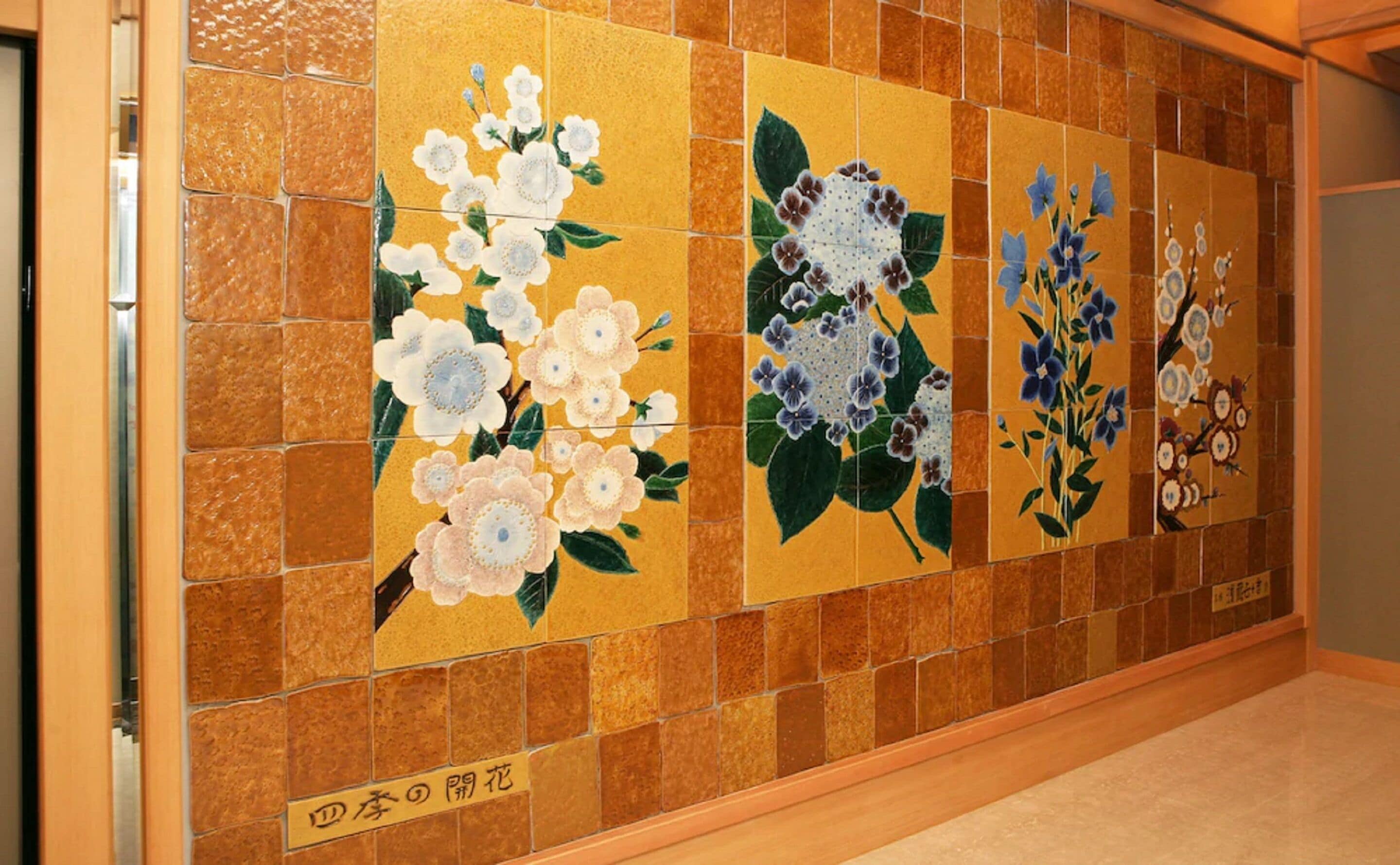 A wall with a series of square tiles featuring floral designs.