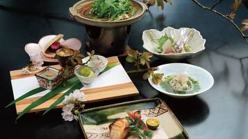 A table with various dishes, including a hot pot, sashimi, and a bowl of soup.