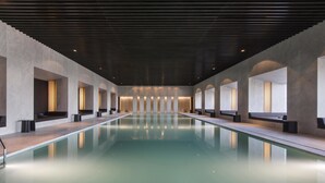 Una piscina interior larga y estrecha, con una cubierta de madera y zonas de estar a ambos lados.