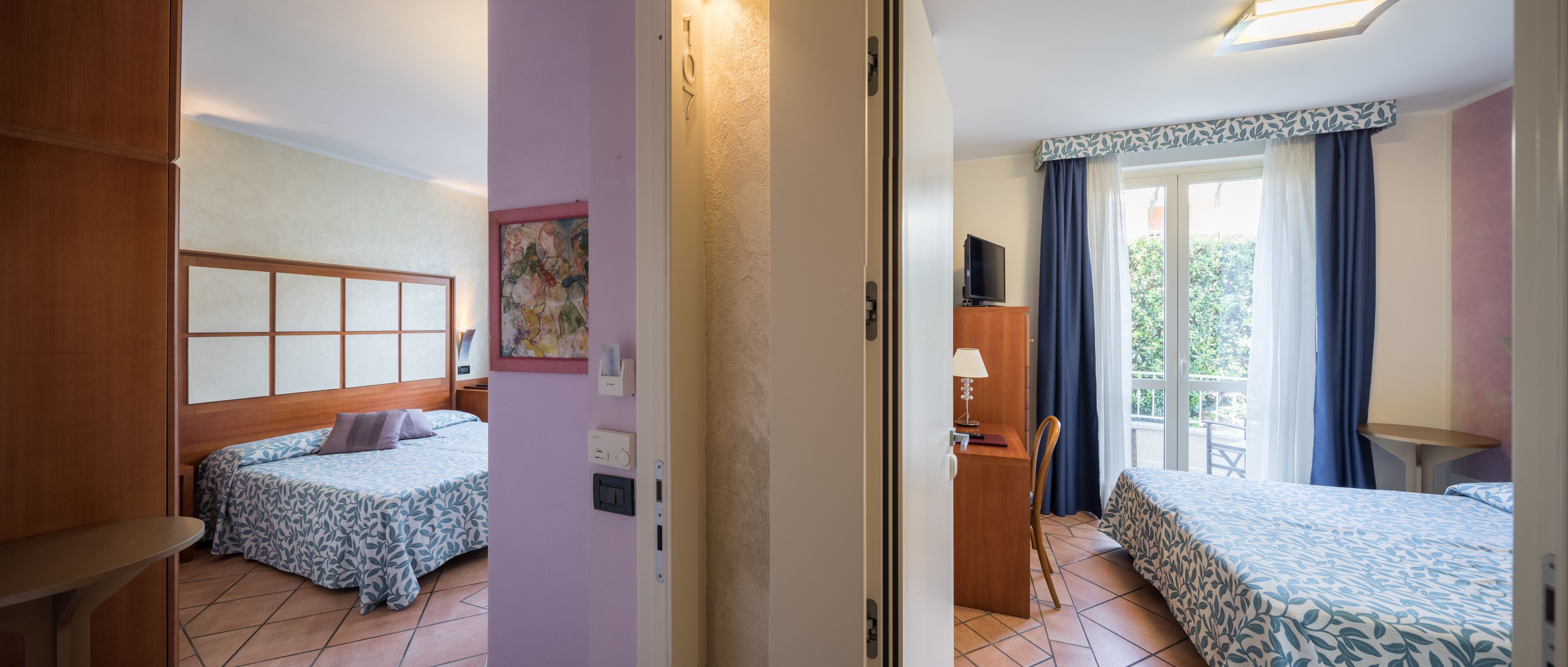 Habitación de hotel con dos camas, un escritorio, una silla y una ventana con cortinas.