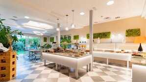 A modern cafe with a checkered floor, a buffet counter with various food items, and a view of the outdoors. - Hotel Luna (Massa)