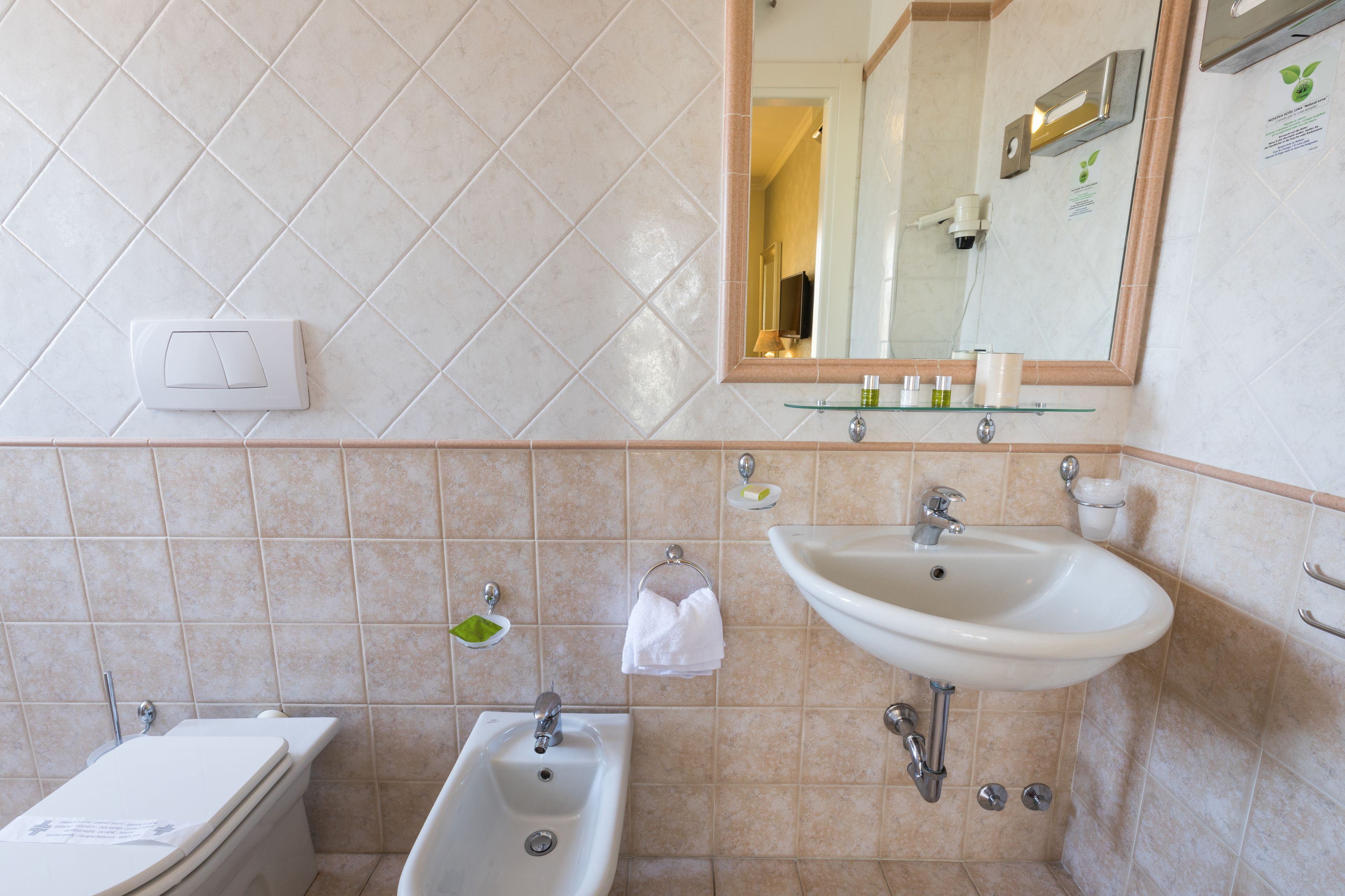 Un bagno con WC, bidet, lavandino e specchio.