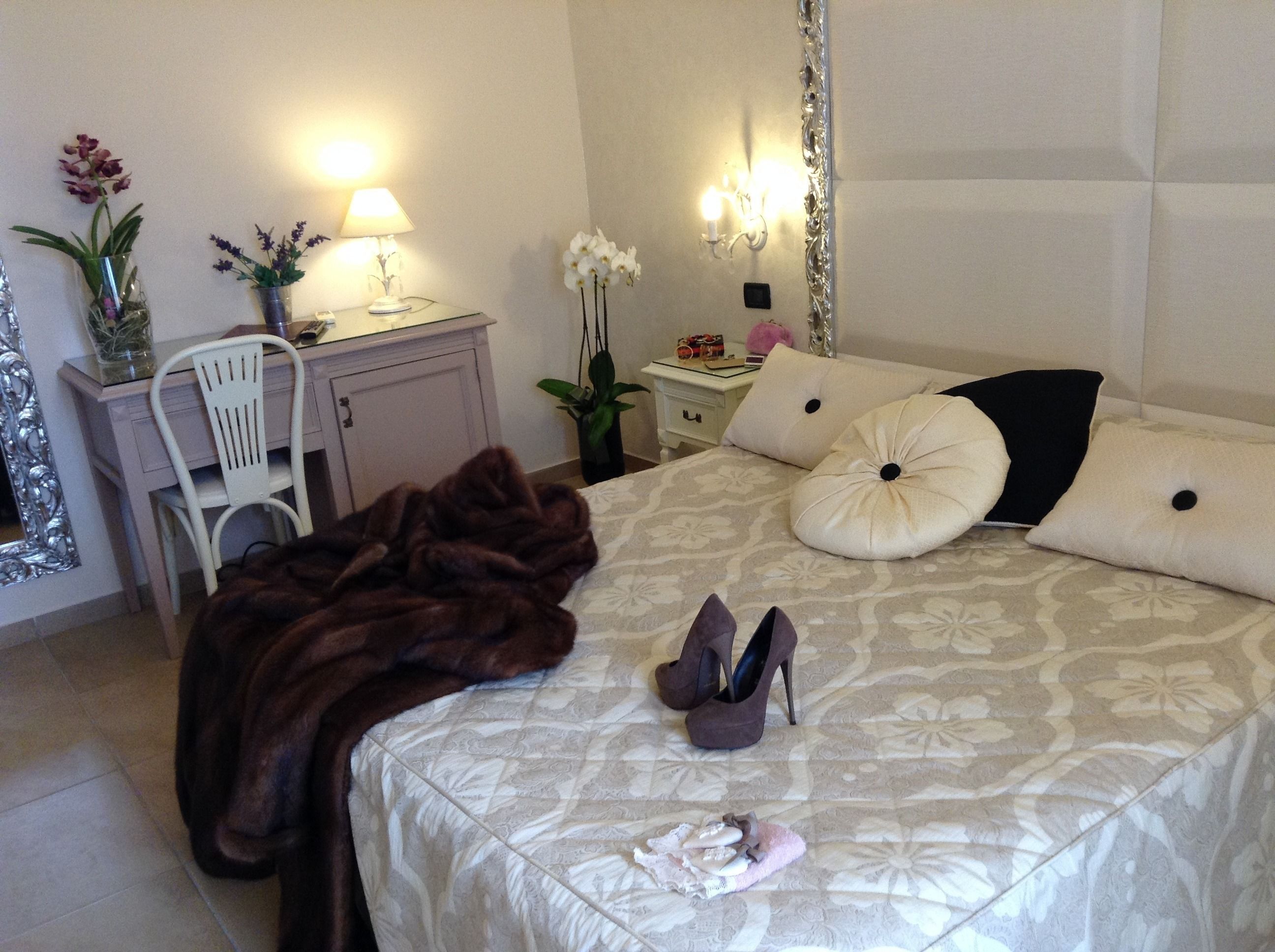 Un dormitorio ordenado con cama, mesitas de noche, una silla y elementos decorativos.