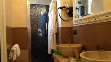 A bathroom with a shower, two sinks, a hairdryer, and a towel rack.
